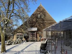 a house in the snow with a bench in front of it at Farmhouse in Nieuwleusen near Lake and Nature in Bergen op Zoom