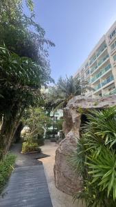 a walkway with a large rock and a building at Amazon Condo, Building B, ground floor with direct pool access in Jomtien Beach