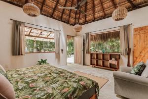 a bedroom with a bed and a couch and windows at Casa Arkaana Eco Retreat in Tulum