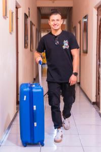 a man walking down a hallway with a blue suitcase at Hotel Posada Stella Maris in Puerto Barrios
