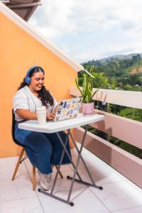 a woman sitting at a table with a laptop at Hotel Posada Stella Maris in Puerto Barrios