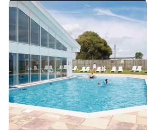 two people in a swimming pool next to a building at A & C Coastal Hideaway with outside Decking in East Mersea