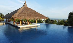 a resort swimming pool with a thatched roof at The Cliff Resort & Residences in Mui Ne