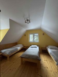 a attic room with two beds and a window at Ośrodek Nad Potokiem in Poręba Wielka