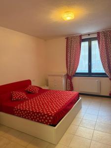 a bedroom with a red bed and a window at Chalet Nonno Ezio in Valdidentro