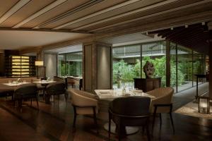 a dining room with tables and chairs and windows at The Ritz-Carlton Kyoto in Kyoto