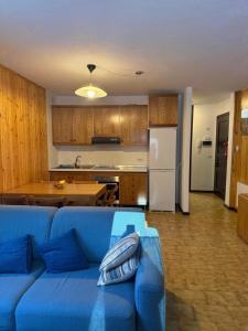 a living room with a blue couch and a kitchen at Chalet Nonno Ezio in Valdidentro