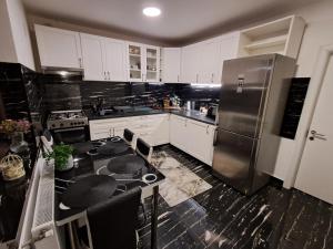 a kitchen with white cabinets and a stainless steel refrigerator at Enjoy VIP House 10 in Măgurele