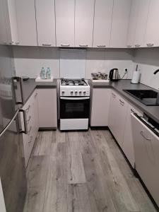 a kitchen with white cabinets and a stove top oven at Beti's Apartment in Zambrów