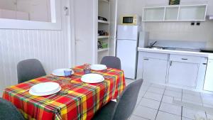 a kitchen with a table and chairs with a table and a tablecloth at Logement meublé proche CHUM, idéal stagiaires et professionnels in Le Lamentin