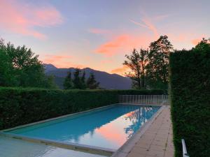 a swimming pool with a sunset in the background at Morz'Inn Vue panoramique sur les montagnes in Morzine