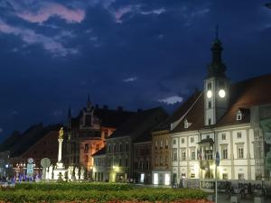a group of buildings with a clock tower at night at Rooms in Maribor Centre in Maribor