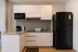 a kitchen with a black refrigerator and white cabinets at Mitik Vista iluminación y comodida in Bogotá