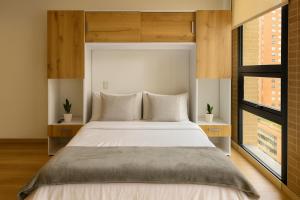 a bedroom with a large bed and two windows at Mitik Vista iluminación y comodida in Bogotá