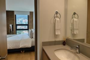 a bathroom with a sink and a bed and a mirror at Mitik Vista iluminación y comodida in Bogotá +39 photos