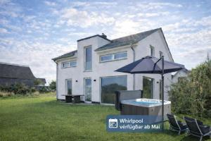a house with an umbrella and a hot tub in the yard at HausLIEBLINGSPLATZ - am Meer - Luxus Villa mit 4 Schlafzimmern, 3 Badezimmern Sauna, Kamin, Weber-Grill und Wallbox in Dranske