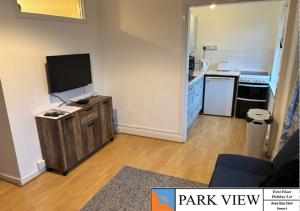 a living room with a kitchen with a tv on a table at Beckington House in Braunton