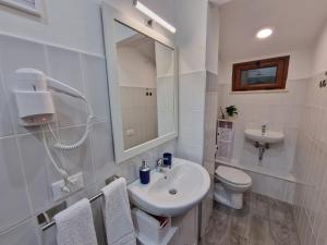 a white bathroom with a sink and a toilet at Vicolo Stretto Guest House Centro storico in Vibo Valentia +14 photos