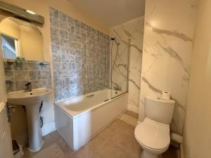 a bathroom with a toilet and a tub and a sink at Broadfield Park Hotel by Belvilla in Rochdale