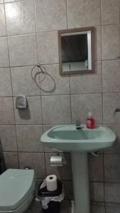a bathroom with a sink and a toilet and a mirror at Pousada Central Quarto 6 in Joinville