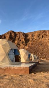 two tents in the desert with a mountain in the background at Wadi Rum Star Haven camp in Wadi Rum