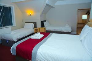 a hotel room with two beds and a red blanket at Broadfield Park Hotel by Belvilla in Rochdale