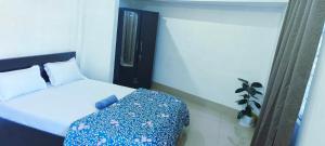 a bedroom with a white bed with a blue blanket at DZ Homestay 1BHK in Dimāpur