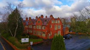 a large red building with a parking lot in front of it at Broadfield Park Hotel by Belvilla in Rochdale