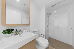 a white bathroom with a toilet and a shower at Brisbane One Views Level 15 2BR Apartment in Brisbane +6 photos