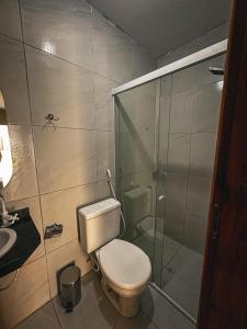 a bathroom with a toilet and a glass shower at Pousada Villa Manzuá in Cascavel +42 photos