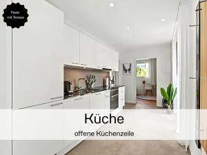 a white kitchen with white cabinets and a kitchen island at Ferienhausträume - ebenerdiges Bodensee Apartment mit Garten und großer Terrasse mit Grill in Kreuzlingen