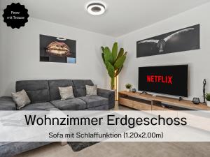 a living room with a couch and a tv at Ferienhausträume - ebenerdiges Bodensee Apartment mit Garten und großer Terrasse mit Grill in Kreuzlingen