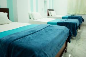 two beds with blue sheets in a room at Hotel Brisas De Calima in Cali +47 photos
