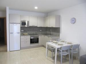 a kitchen with white appliances and a table and chairs at Apartamento " El Pueblo" in Mogán