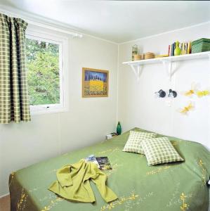a bedroom with a bed with green sheets and a window at ZEcamping 3 étoiles - bord de Loire - proximité directe des châteaux in Sully-sur-Loire