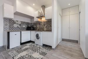 a kitchen with white cabinets and a washer and dryer at Olma in Nice