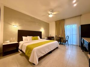 ein Hotelzimmer mit einem großen Bett und einem Schreibtisch in der Unterkunft Hotel Ikzam Palenque in Palenque