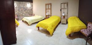 a bedroom with two beds with yellow covers on them at Cabaña Aklla in Tilcara