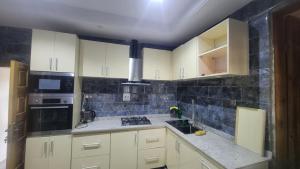 a kitchen with white cabinets and black appliances at Lakatabu Apartments in Mama