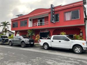 two trucks parked in front of a red building at Hotel las palmas in Rosa Zárate