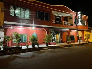 a red building with potted plants in front of it at Hotel las palmas in Rosa Zárate