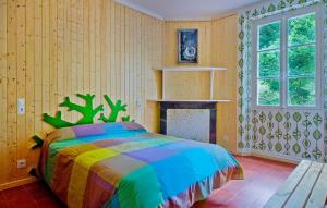 1 dormitorio con 1 cama colorida y chimenea en Gitê Casa Rural El Ambigú, en Urdos