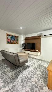 a living room with a couch and a television at Quarto de vila na Urca in Rio de Janeiro