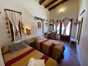 a room with two beds and a table in it at Hosteria La Pushka in Purmamarca