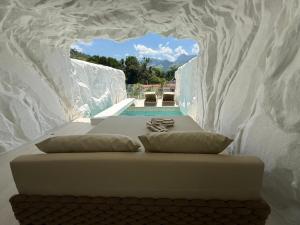 a white bed with pillows and a pool in a room at Pousada Apple House Paraty in Paraty