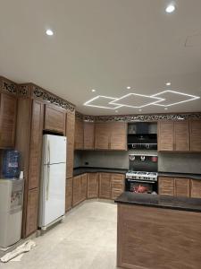 a kitchen with wooden cabinets and a white refrigerator at شاليه الدرة Durra Chalet in Amman