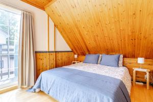 a bedroom with a bed and a large window at Hakuba Powder Cottage in Hakuba