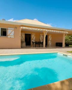 a large blue swimming pool in front of a house at La villa Yuna in Le Vauclin