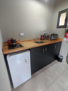 a kitchen with a counter and a sink and a refrigerator at Posada Abrazo Serrano en Carpintería in Carpintería +9 photos