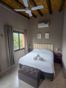 a bedroom with a white bed with a ottoman and a window at Posada Abrazo Serrano en Carpintería in Carpintería